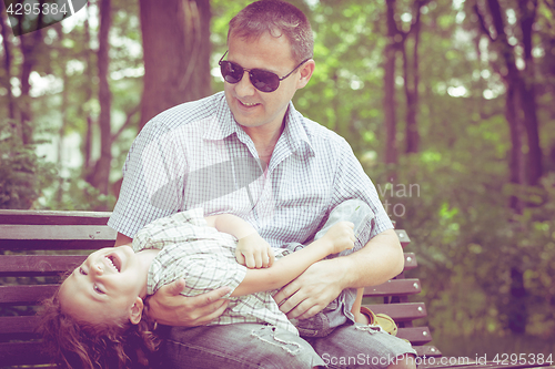 Image of Father and son playing at the park on bench at the day time.