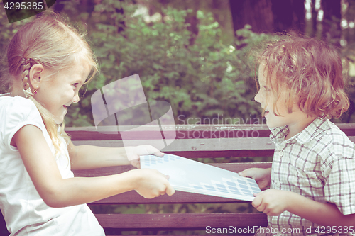 Image of Two happy children  playing near the tree at the day time.