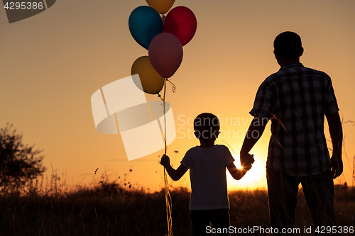 Image of Father and son playing at the park at the sunset time.