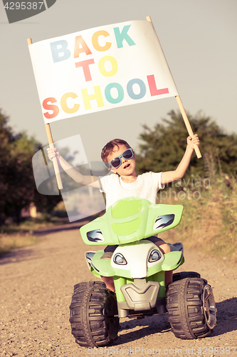 Image of Happy little boy playing on road at the day time. He driving on 