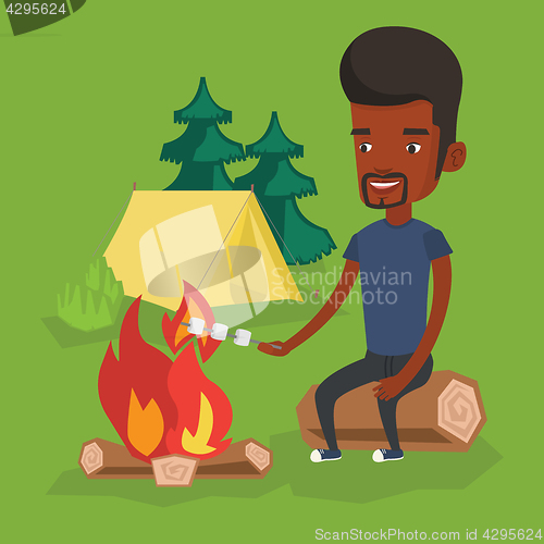 Image of Man roasting marshmallow over campfire.