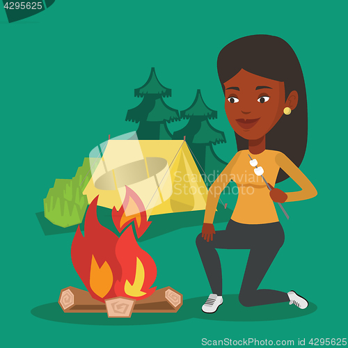 Image of Woman roasting marshmallow over campfire.