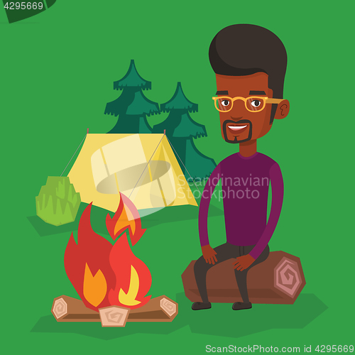 Image of Man sitting on log near campfire in the camping.