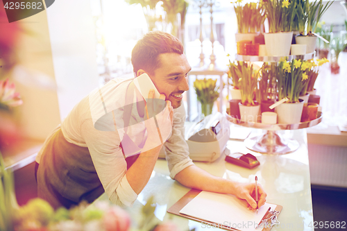 Image of man with smartphone making notes at flower shop