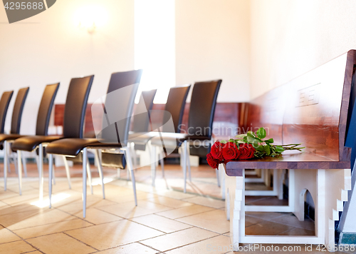 Image of red roses on bench at funeral in church