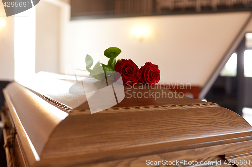 Image of red rose flowers on wooden coffin in church