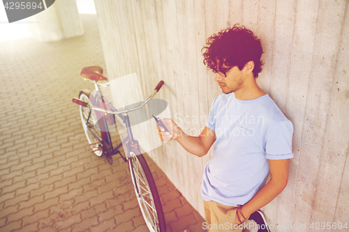 Image of man with smartphone and fixed gear bike on street