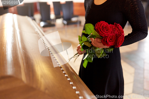 Image of woman with red roses and coffin at funeral