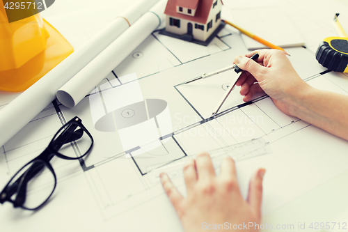 Image of close up of hands with compass measuring blueprint