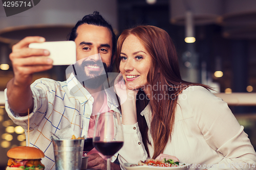 Image of couple taking selfie by smartphone at restaurant