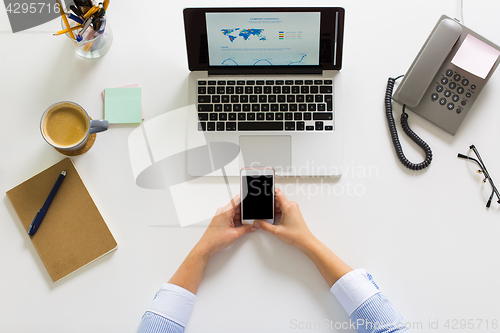 Image of businesswoman with laptop and smartphone at office