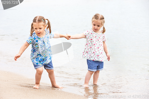 Image of Children on the sea beach. Twins going along sea water.