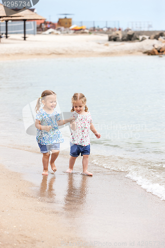 Image of Children on the sea beach. Twins going along sea water.