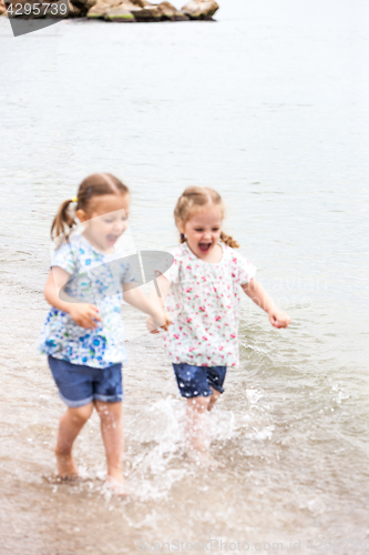 Image of Children on the sea beach. Twins going along sea water.