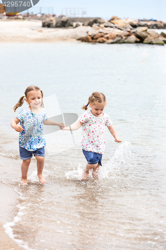 Image of Children on the sea beach. Twins going along sea water.