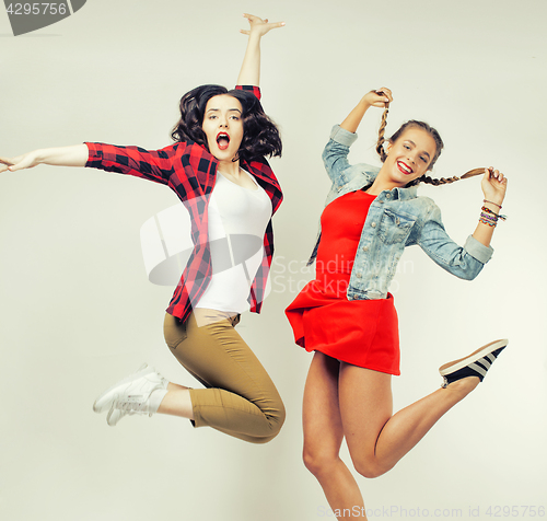 Image of two pretty brunette and blonde teenage girl friends jumping happy smiling on white background, lifestyle people concept 