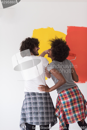 Image of multiethnic couple painting interior wall