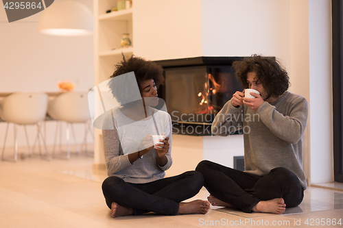 Image of multiethnic couple  in front of fireplace