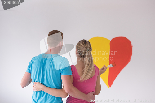 Image of couple are painting a heart on the wall