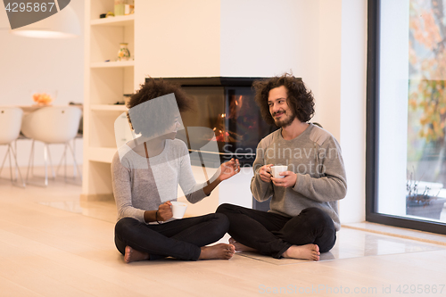 Image of multiethnic couple  in front of fireplace