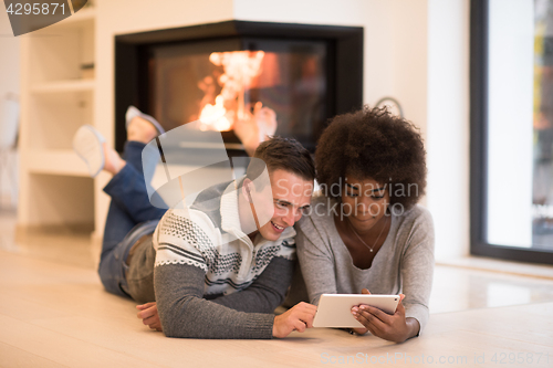 Image of multiethnic couple using tablet computer on the floor