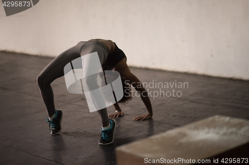 Image of black woman standing in bridge pose