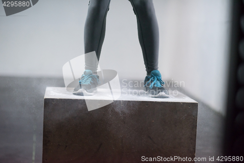 Image of black woman is performing box jumps at gym