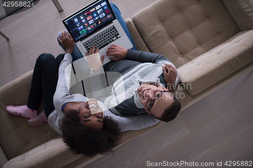 Image of happy multiethnic couple relaxes in the living room