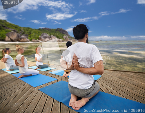 Image of group of people making yoga exercises outdoors