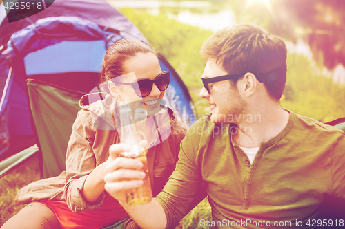 Image of happy couple clinking drinks at campsite tent