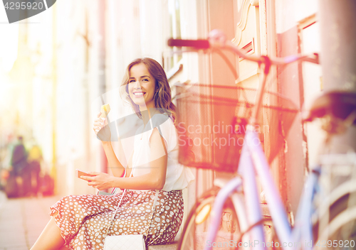 Image of happy woman with smartphone, bike and ice cream