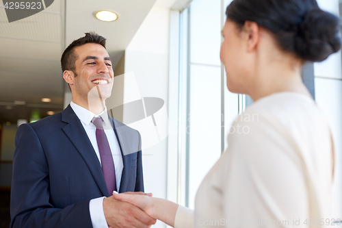 Image of smiling business people shaking hands at office