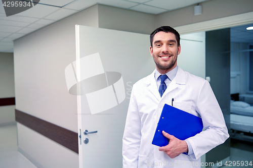 Image of happy doctor with clipboard at hospital corridor