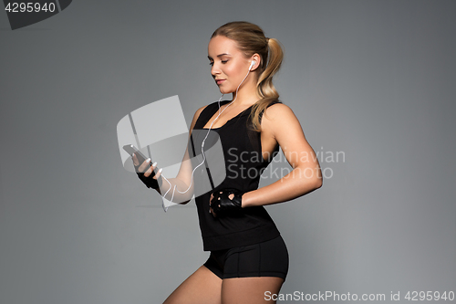 Image of woman with smartphone and earphones in gym
