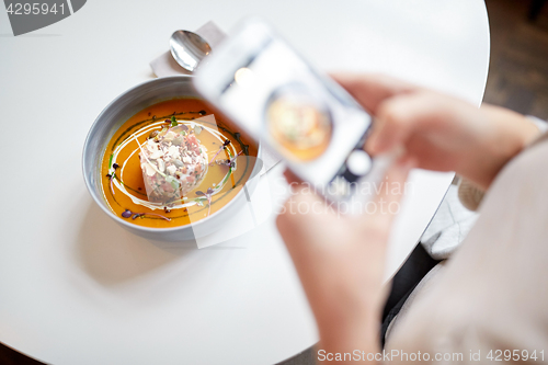 Image of woman with smartphone photographing food at cafe