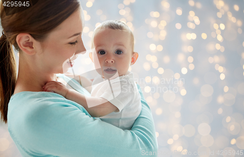 Image of happy young mother with little baby over lights