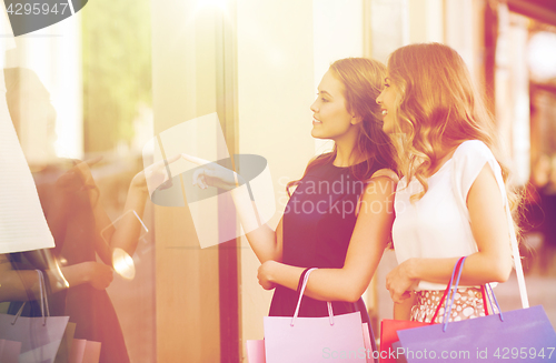 Image of happy women with shopping bags at shop window