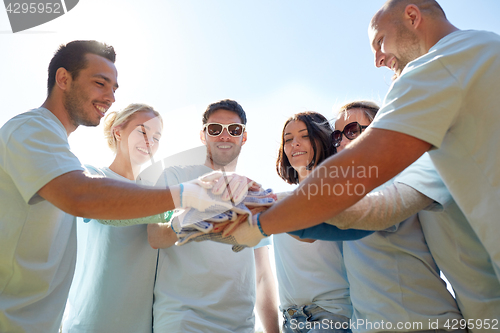 Image of group of volunteers putting hands on top outdoors