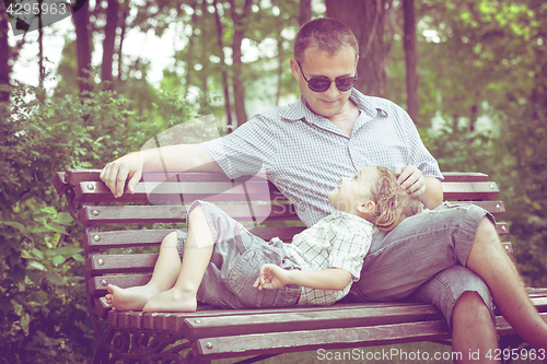 Image of Father and son playing at the park on bench at the day time.