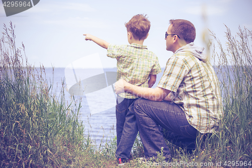 Image of Father and son playing at the park near lake at the day time.