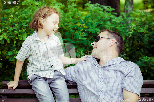 Image of Father and son playing at the park on bench at the day time.