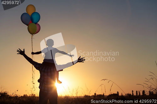 Image of Father and son playing at the park at the sunset time.