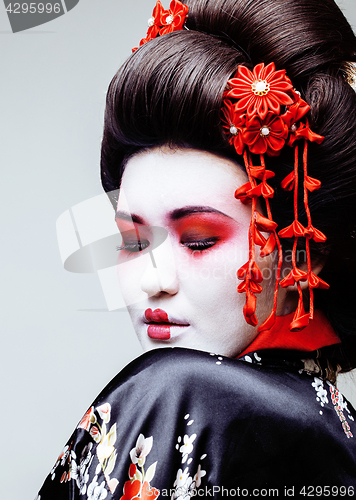 Image of young pretty geisha in black kimono among sakura, asian ethno close up