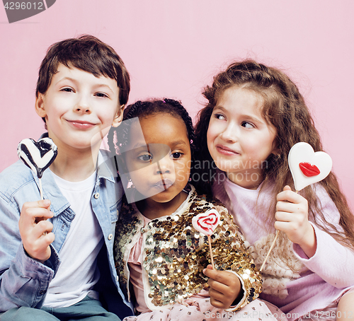 Image of lifestyle people concept: diverse nation children playing together, caucasian boy with african little girl holding candy happy smiling 