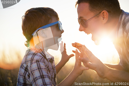 Image of Father and son playing on the field at the day time.