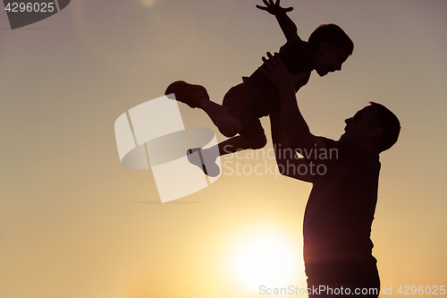 Image of Father and son playing in the park at the sunset time.