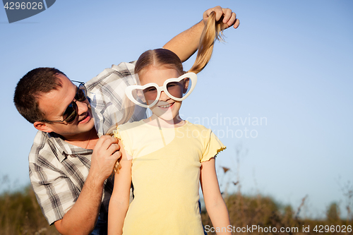 Image of Dad and daughter in sunglasses playing near a house at the day t