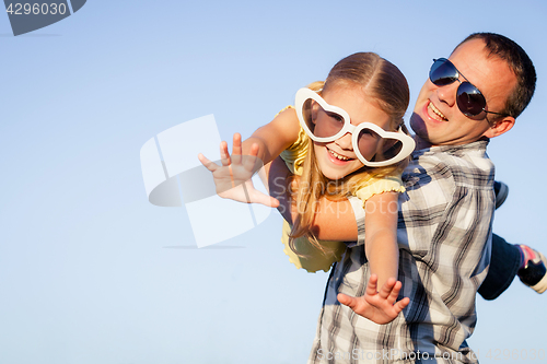 Image of Dad and daughter in sunglasses playing near a house at the day t