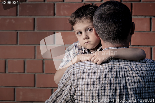 Image of Portrait of sad son hugging his dad