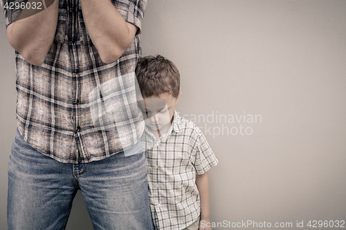 Image of sad son hugging his dad near wall